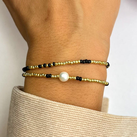 Armbånd Kjersti i sort og gull på håndledd