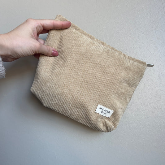 Clutch i kordfløyel holdt i hånden
