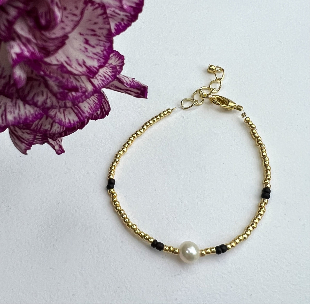 Armbånd sort og gull med ferskvannsperle og blomster